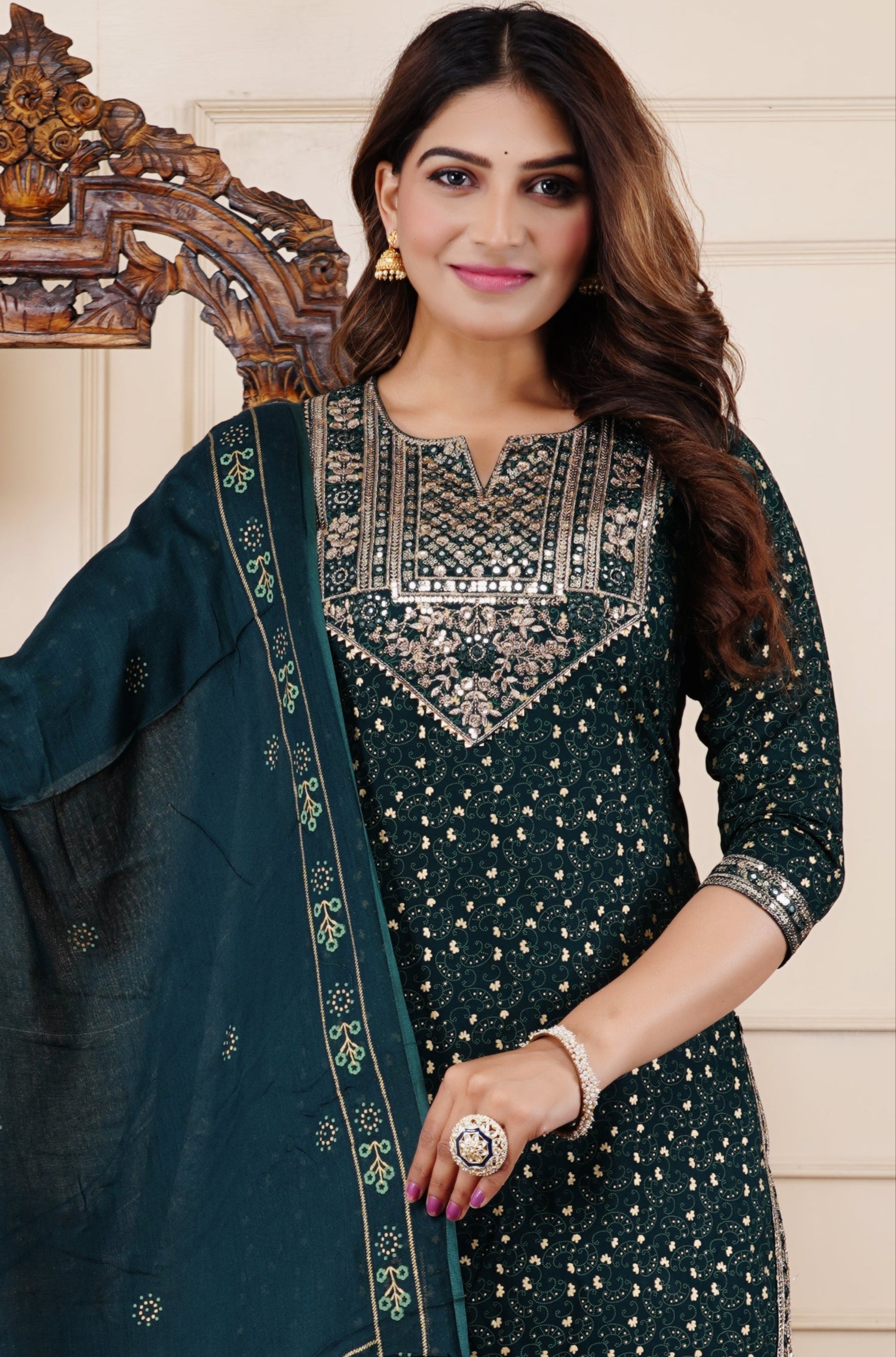 Woman holding a green saree with a matching outfit in a decorated room.